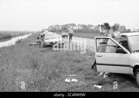 Spotters Schiphol, Roadside Tourist Schiphol, Schiphol, 15-06-1989 Whizgle News, Dutch Desk, i Paesi Bassi, 1950-2000 Un gruppo di persone si trova lungo una strada rurale, osservando un canale e catturando il momento con le telecamere. Diverse auto sono parcheggiate nelle vicinanze, mentre alcune persone sono impegnate in una conversazione e altre sono sedute sull'erba, godendosi il paesaggio. Il paesaggio presenta campi e alberi sullo sfondo. Foto Stock