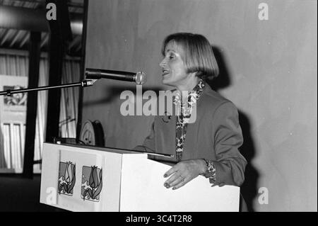 Presentazione Provinciale Ufficio Turistico Nord Olanda, 20-10-1993 Whizgle News, Dutch Desk, Paesi Bassi, 1950-2000 Una donna in un vestito professionale si erge su un podio, parlando in un microfono. Sembra impegnata e sicura di sé mentre si rivolge a un pubblico, con opere d'arte colorate visibili sullo sfondo. Foto Stock