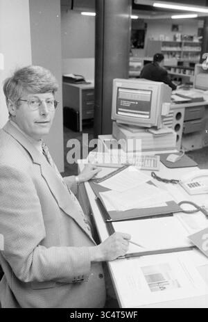 Sig. Sintenie, Rabobank, H'stede, Heemstede, Paesi Bassi, 30-10-1994 Whizgle News, Dutch Desk, Paesi Bassi, 1950-2000 Una persona siede a una scrivania in un ambiente di ufficio, circondato da documenti cartacei e un computer. Sono concentrati sulle loro attività, indossando occhiali e un blazer di colore chiaro. In background, un altro individuo è visto lavorare in una scrivania separata. Foto Stock