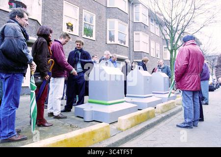 Messa in servizio di contenitori per rifiuti sotterranei ad Amsterdam, Amsterdam, Paesi Bassi, 16-12-1993 Whizgle News, Dutch Desk, i Paesi Bassi, 1950-2000 Un gruppo di persone si è riunito per strada, discutendo e osservando grandi contenitori di riciclaggio posti lungo il marciapiede. Sembrano impegnati in una conversazione, con alcuni che tengono in mano ombrelli e altri che sembrano riflettere sull'iniziativa di riciclaggio. Foto Stock