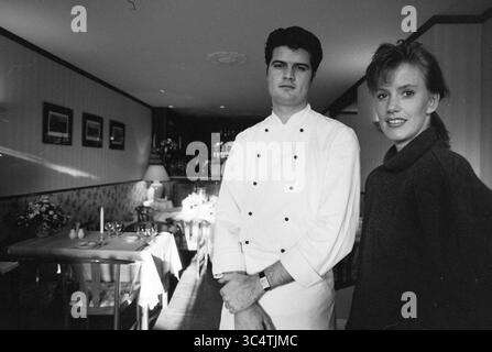 Ristorante 't Stille Water, 01-02-1991 Whizgle News, Dutch Desk, Paesi Bassi, 1950-2000 Uno chef in uniforme bianca si erge con le braccia incrociate, accanto a una donna sorridente vestita con un comodo maglione. Si trovano in un ristorante elegante, completo di tavoli elegantemente allestiti e di una calda atmosfera. La scena suggerisce un mix di professionalità e cameratismo nel mondo culinario. Foto Stock