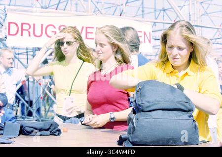 Dance Valley Goers, 03-08-2001 Whizgle News, Dutch Desk, Paesi Bassi, 1950-2000 Un gruppo di tre giovani donne si riunisce, impegnata in una conversazione in un evento all'aperto. Una donna regola i suoi capelli, mentre un'altra controlla la sua borsa, e la terza guarda con attenzione. Sono circondate da un'atmosfera movimentata, che suggerisce un incontro organizzato. Foto Stock