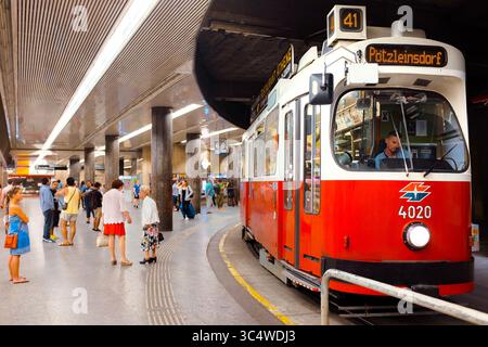 I passeggeri attendono su una piattaforma curva accanto a un classico tram rosso sulla linea 41, che mostra l'efficiente trasporto pubblico della città e il fascino urbano nostalgico. Foto Stock