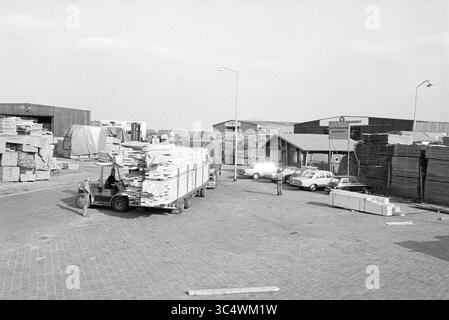 Wood Transshipment Beverwijk, Hout, Beverwijk, Paesi Bassi, 03-10-1980 Whizgle News, Dutch Desk, Paesi Bassi, 1950-2000 Un affollato cantiere di legname con pila di legno e compensato, con veicoli parcheggiati nelle vicinanze. I lavoratori vengono visti scaricare materiali da un camion, mentre edifici e pile di pannelli di legno formano lo sfondo. Foto Stock