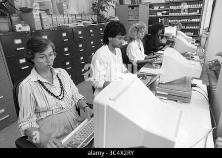 Ladies at Screens at Velsen Town Hall, Computers, Town Hall, Velsen, 22-09-1988 Whizgle News, Dutch Desk, Paesi Bassi, 1950-2000 Un gruppo di quattro persone che lavorano diligentemente nelle loro postazioni informatiche in un ufficio, si è concentrato sui loro schermi e sulle loro attività, circondato da armadietti di archiviazione. Foto Stock