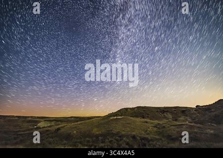 12 agosto 2017 - Canada - Una pista satellitare con il satellite che si libra forse per fornire un sentiero pulsante mentre viaggiava attraverso il cielo da nord a sud (da sinistra a destra), variando in luminosità. Questo serve come esempio di questo tipo di satellite. Potrebbe essere un razzo esaurito, non un satellite funzionante. ..preso come parte di un set time-lapse e impilabile per la pioggia meteorica Perseide. Questi fotogrammi sono stati girati in 6 minuti. La Luna che si sta alzando e si sta abbassando illumina il cielo a destra. ..questa è una pila di 14 immagini per il satellite e il cielo, unite con la modalità Schiarisci, e 4 per la Foto Stock