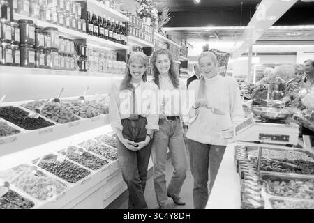 Staff C´est Bon, Schalkwijk, 25-09-1991 Whizgle News, Dutch Desk, Paesi Bassi, 1950-2000 tre donne sorridono in un vivace mercato, circondato da una serie di vasi colorati e contenitori pieni di vari alimenti, tra cui frutta secca e noci. L'atmosfera vivace suggerisce una piacevole esperienza di shopping. Foto Stock