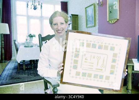 Ellen Kerkvliet, Haarlem, Paesi Bassi, 14-05-2002 Whizgle News, Dutch Desk, i Paesi Bassi, 1950-2000 Una donna sorridente in un abito bianco racchiude un pezzo decorativo incorniciato con vari strumenti di lavorazione, circondato da un interno accogliente con una zona pranzo sullo sfondo. Foto Stock