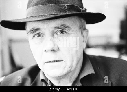 Ritratto Gerrit van Dijk, 11-11-1998 Whizgle News, Dutch Desk, Paesi Bassi, 1950-2000 un uomo anziano con un cappello scuro guarda intensamente, il suo volto segnato da linee profonde che raccontano storie di una vita vissuta, rivelando un mix di saggezza e contemplazione. Foto Stock