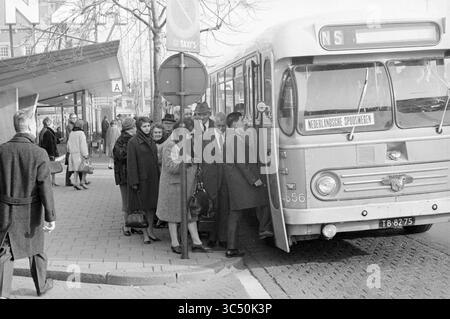 Autobus NZH utilizzato come trasporto temporaneo per i passeggeri del treno, Haarlem, The Netherlands Whizgle News, Dutch Desk, The Netherlands, 1950-2000 Un gruppo di persone sta salendo su un autobus in una fermata della città, con alcuni passeggeri che trasportano bagagli. Nelle vicinanze, un uomo sta in piedi casualmente mentre gli altri aspettano in fila. L'atmosfera suggerisce una tipica giornata movimentata in un ambiente urbano. Foto Stock