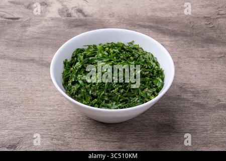 Strisce di kale cotte, tipico fiancata brasiliana feijoada in una ciotola su tavola di legno. Foto Stock