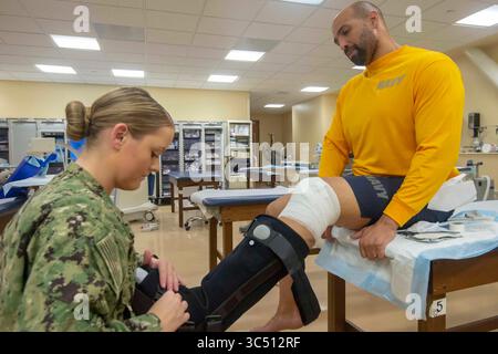 2 dicembre 2019 - San Diego, California, Stati Uniti - Hospital Corpsman 3a Classe Dallas Evernden, un tecnico ortopedico assegnato al Naval Medical Center San Diego (NMCSD), applica uno stivale con movimento controllato alla caviglia all'Hospital Corpsman 2a Classe Travis Jones presso l'ospedale, 2 dicembre. Il reparto ortopedico è responsabile dell'applicazione di getti, stecche e bretelle ai pazienti con articolazioni e ossa ferite. La missione di NMCSDâ è preparare i membri del servizio a schierarsi a sostegno delle forze operative, fornire servizi sanitari di alta qualità e plasmare il futuro della medicina militare attraverso l'istruzione, tr Foto Stock
