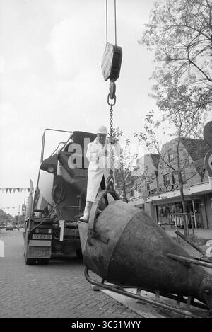 Punto più alto del pozzo a Heemstede, Heemstede, Paesi Bassi, 19-06-1991 Whizgle News, Dutch Desk, i Paesi Bassi, 1950-2000 Un lavoratore in tuta bianca gestisce una gru per sollevare un grande oggetto metallico da un camion, circondato da alberi ed edifici adornati con decorazioni festose. Foto Stock