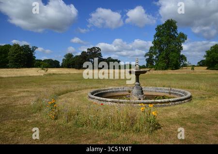 Fontana in pietra in disuso in un prato a Hatchlands Park, Surrey, Inghilterra, Regno Unito. Scena estiva, 8 luglio 2025. Foto Stock
