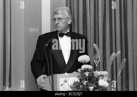 Schiphol Airport, cena, 30-09-1994 Whizgle News, Dutch Desk, Paesi Bassi, 1950-2000 Un uomo in abito formale si erge su un podio, preparandosi a parlare, con un microfono davanti a lui e un mazzo di fiori nelle vicinanze. Foto Stock