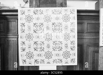 Mostra di piastrelle, mostre, 02-08-1972 Whizgle News, Dutch Desk, Paesi Bassi, 1950-2000 Un tessuto decorativo caratterizzato da un pattern ripetuto di intricati motivi floreali e geometrici, esposto su uno sfondo in legno. La disposizione presenta un armonioso mix di forme e motivi, creando una composizione visivamente accattivante. Foto Stock
