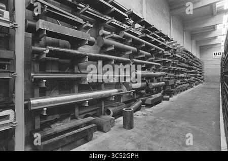 Staff + Interior Uddeholm, Uddeholm NV, 18-02-1971 Whizgle News, Dutch Desk, Paesi Bassi, 1950-2000 Un'area di stoccaggio strutturata rivestita con varie aste e tubi in metallo, ordinatamente disposta su rack, che presenta una miscela di dimensioni e forme diverse, illuminata da una luce soffusa. Foto Stock
