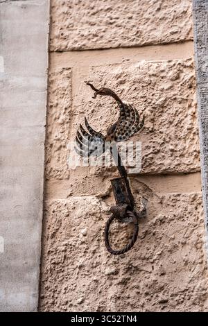 Anello da parete in ferro battuto con design a forma di uccello stilizzato, possibilmente un portatorcia o un anello di attacco, su una strada medievale nel centro storico di Assisi, Umbria Foto Stock