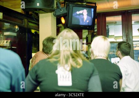 Attacco a PIM Fortuyn studio Haarlem, Haarlem, Paesi Bassi, 05-05-2002 Whizgle News, Dutch Desk, paesi Bassi, 1950-2000 Un gruppo di persone guarda uno schermo televisivo, in cui un uomo con un abito saluta. La scena cattura un momento di concentrazione e coinvolgimento, con alcuni individui che sembrano essere in un abbigliamento informale e seduti in un bar o ristorante. Foto Stock