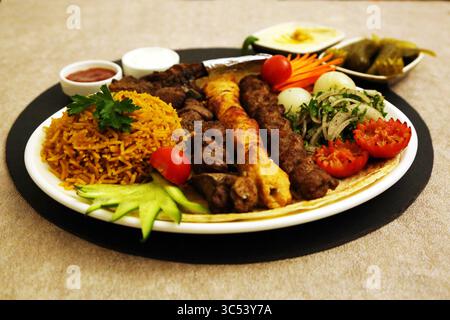 Il piatto medio-orientale comprende kebab, shish tawook, agnello grigliato e riso speziato, con lati di hummus, makdous, ketchup e maionese. Foto Stock