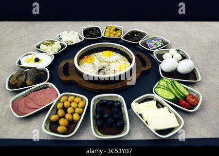 Colazione tradizionale levantina a buffet con formaggi assortiti, labnee, olive, affettati, sottaceti, marmellate e uova con il lato soleggiato al centro. Foto Stock