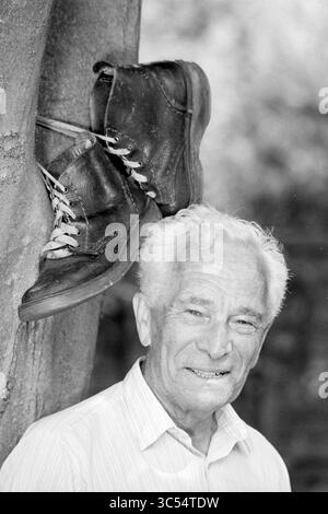 Oorschot 50x Nijmegen evento di quattro giorni, Nijmegen, 12-07-1994 Whizgle News, Dutch Desk, Paesi Bassi, 1950-2000 un uomo anziano con un sorriso caldo si erge accanto ad un albero, da cui appendono un paio di scarpe intemprate. La scena cattura un momento di nostalgia e storia, mescolando l'esperienza umana con un'esposizione unica di calzature. Foto Stock