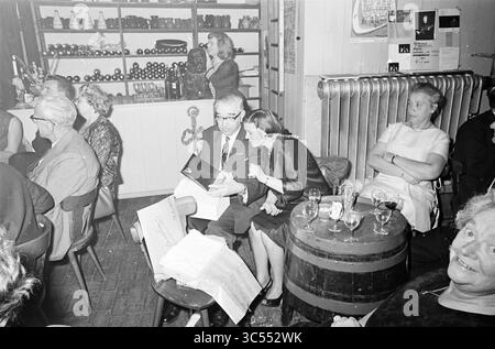 Riunione dei dipendenti di Haarlems Dagblad a Waag, Haarlem, Damstraat, Paesi Bassi, 16-06-1965 Whizgle News, Dutch Desk, Paesi Bassi, 1950-2000 Un vivace raduno in un ambiente accogliente, caratterizzato da un mix di clienti elegantemente vestiti impegnati in conversazione. Una coppia si siede vicino a un piccolo tavolo, condividendo risate e sguardi su un menu. Sullo sfondo, gli scaffali rivestiti di bottiglie aggiungono un'atmosfera calda e invitante, mentre una folla diversificata gode dell'atmosfera e della compagnia reciproca. Foto Stock