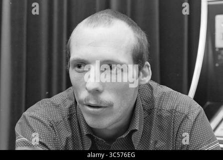 Ritratto di Danny Lensen, calciatore di EDO, Personen, 19-11-1981 Whizgle News, Dutch Desk, Paesi Bassi, 1950-2000 Un uomo dall'espressione premurosa è seduto a un tavolo e indossa una camicia a motivi geometrici con colletto abbottonato. I suoi capelli corti e i baffi completano il suo comportamento mirato, mentre appare in profondità nella conversazione. Lo sfondo è costituito da una tenda scura, che aumenta l'intensità complessiva della scena. Foto Stock