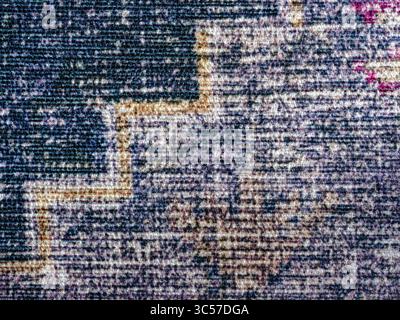 I motivi geometrici sono visibili nel tessuto di un tappeto di zona usurato Foto Stock