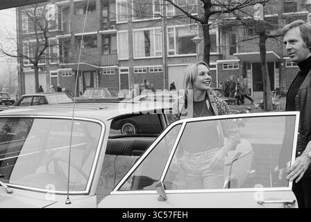 Monique van der Ven prende il test di guida, C.B.R., 07-03-1974 Whizgle News, Dutch Desk, Paesi Bassi, 1950-2000 Una coppia sta accanto a un'auto d'epoca, con la donna che sorride mentre esce, mentre l'uomo guarda. Sullo sfondo, una vivace scena stradale si snoda tra pedoni e auto parcheggiate, suggerendo un'atmosfera urbana vivace. Foto Stock