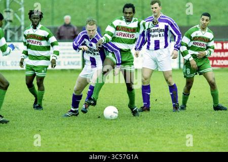 Football Spaarnwoude - @@, 24-11-2001 Whizgle News, Dutch Desk, Paesi Bassi, 1950-2000 Una dinamica scena calcistica con giocatori di due squadre che competono per il possesso della palla su un campo erboso, con giocatori che indossano divise a strisce verdi e bianche e divise viola e bianche, che mostrano il lavoro di squadra e l'atletismo. Foto Stock