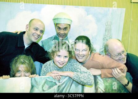 Gruppo teatrale Eglentier, Haarlem, Paesi Bassi, 14-01-1999 Whizgle News, Dutch Desk, i Paesi Bassi, 1950-2000 Un gruppo di sei persone posa insieme a sorrisi allegri, interagendo giocosamente dietro uno sfondo dipinto. La scena cattura un senso di divertimento e cameratismo, con due adulti e un bambino in primo piano, mentre gli altri si appoggiano da dietro, contribuendo a creare un'atmosfera leggera. Foto Stock
