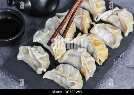 Deliziosi gyoza giapponesi, pronti per essere gustati con una salsa salata. Un antipasto o un pasto ideale da consumare con le bacchette. Foto Stock