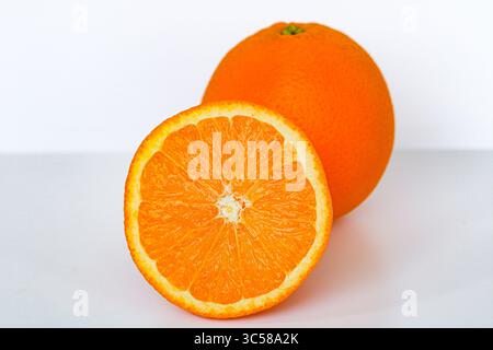 Vivaci arance sunkiste. Un intero intero, uno a metà, catturato con una luce nitida su uno sfondo bianco. Foto Stock