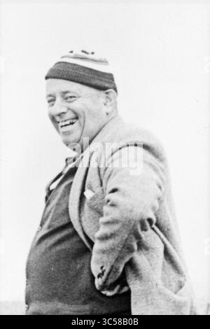 Uomo ritratto, 00-02-1969 Whizgle News, Dutch Desk, Paesi Bassi, 1950-2000 Un uomo con un'espressione gioviale, che indossa un comodo cappello a righe e un cappotto sartoriale, si erge con una postura rilassata, apparentemente godendo di un momento spensierato. Foto Stock