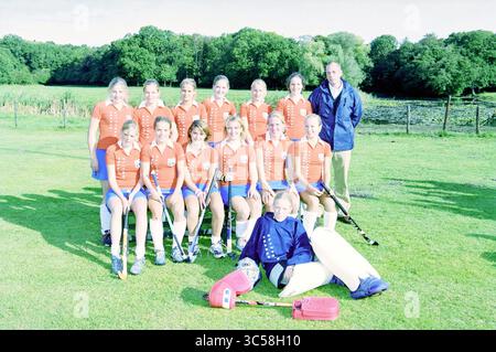 Gruppo giovanile, Bloemendaal hockey, 26-09-2003 Whizgle News, Dutch Desk, Paesi Bassi, 1950-2000 Un gruppo di giovani donne vestite con uniformi sportive rosse e blu si posano insieme su un campo erboso, mostrando il loro spirito di squadra. Sono raggiunti da un allenatore, e un portiere siede davanti, mettendo in evidenza il loro cameratismo e la loro dedizione allo sport dell'hockey su prato. Foto Stock