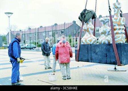 Opere d'arte, vasi in ceramica, Hillegom, 03-11-1998 Whizgle News, Dutch Desk, i Paesi Bassi, 1950-2000 Un gruppo di quattro persone si riunisce intorno a una scultura colorata sollevata da una gru, impegnata in discussioni e osservazioni mentre è preparata per l'installazione in un ambiente urbano. Foto Stock