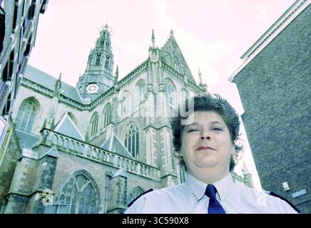 Petra Dekkers, Haarlem, Paesi Bassi, 22-07-1999 Whizgle News, Dutch Desk, i Paesi Bassi, 1950-2000 Una donna in uniforme si trova di fronte a una grande chiesa storica con intricati dettagli architettonici, guglie torreggianti e un orologio. L'ambientazione trasuda un senso di tradizione e orgoglio civico. Foto Stock