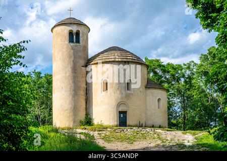 Questa storica rotunda romanica, dedicata a San Giorgio, si erge maestosamente in cima al monte Rip in Cechia. Circondato da vegetazione lussureggiante e sotto un cielo luminoso, invita all'esplorazione. Foto Stock