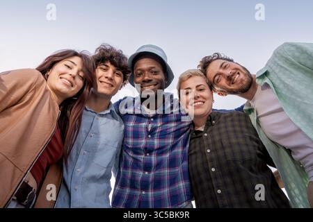Sorridenti giovani adulti che si divertono insieme in un gruppo diversificato, divertimento all'aperto e connessione Foto Stock