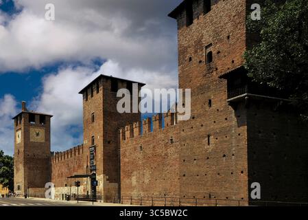 Formidabile fortezza di Castelvecchio a Verona, Veneto, in Italia, a metà del 1300, roccaforte della Scala o signori scaligeri della città, ben difesa da fossati profondi, ponti levatoi, massi in mattoni e merli a coda d'rondine per proteggere gli arcieri medievali. La facciata sud-est su corso Castelvecchio ha tre torri, tra cui la porta centrale e (a sinistra) una torre dell'orologio costruita intorno al 1206 d.C. Foto Stock