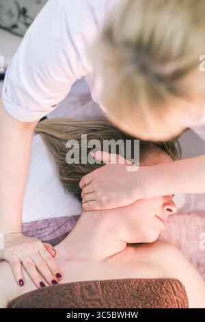 Una donna sta ricevendo un massaggio da una donna. La donna che fa il massaggio indossa una camicia bianca Foto Stock