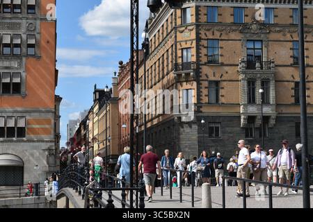 Vivace scena di strada nel centro di Stoccolma, in Svezia, con architettura storica e gente che cammina sotto un cielo estivo soleggiato. Un vibrante momento urbano nel Foto Stock