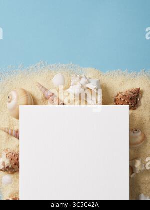 Tela bianca frammentata adagiata su una superficie sabbiosa circondata da conchiglie bianche e marroni su sfondo blu pastello. Spazio per testo, pubblicità, invit Foto Stock