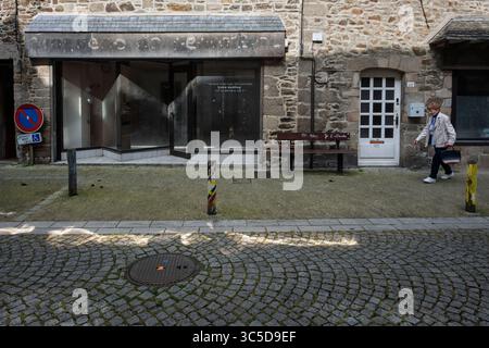 Una donna che passa davanti a un negozio chiuso, Lamballe, Côtes-d'Armor, Bretagna, Francia Foto Stock
