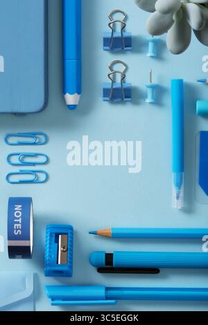 Cornice blu per cancelleria di penne in feltro, matite, gomma, graffette, spille, affilatrice, cucitrice. Sfondo azzurro, spazio per il testo. Foto Stock