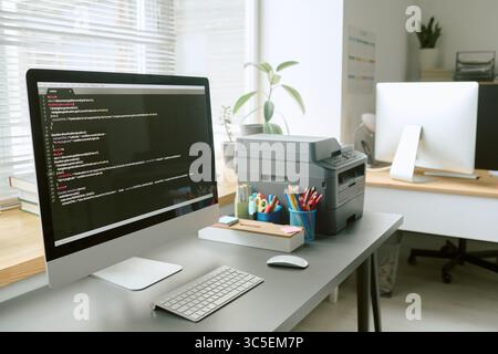 Modern Office Workspace con computer desktop che visualizza il codice di programmazione Foto Stock