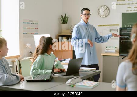 Donna caucasica di mezza età che insegna diversi adolescenti programmazione informatica Foto Stock