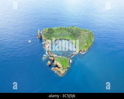 Vista aerea di un'isola vulcanica con una laguna turchese annidata nel suo cratere, circondata dal mare blu profondo, Vila Franca do campo, Azzorre, Portogallo. Foto Stock