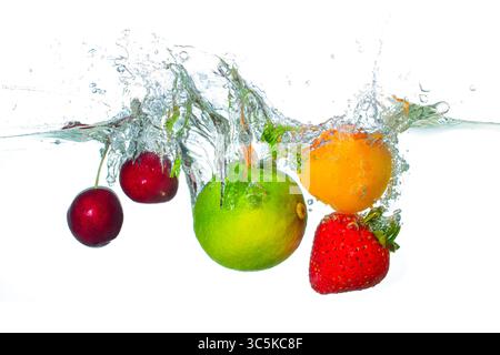 Frutta colorata, tra cui ciliegie dolci, lime, albicocca e fragola, spruzzata in acqua, creare onde dinamiche e goccioline, enfatizzando la freschezza Foto Stock